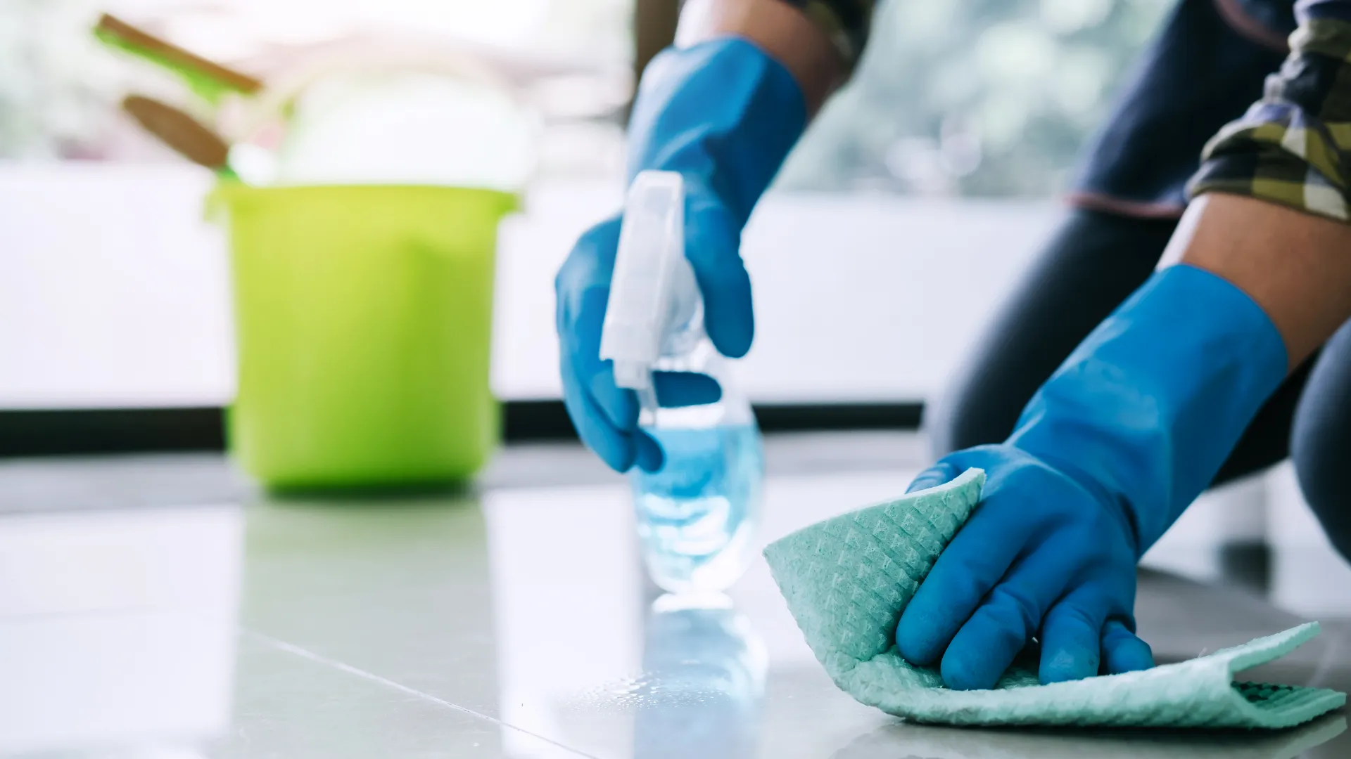 Man spraying and wiping down floor with gloves on